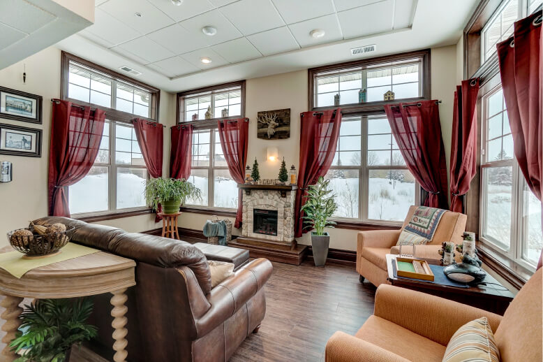 Cozy common area with fireplace and large windows in a senior living community unit.