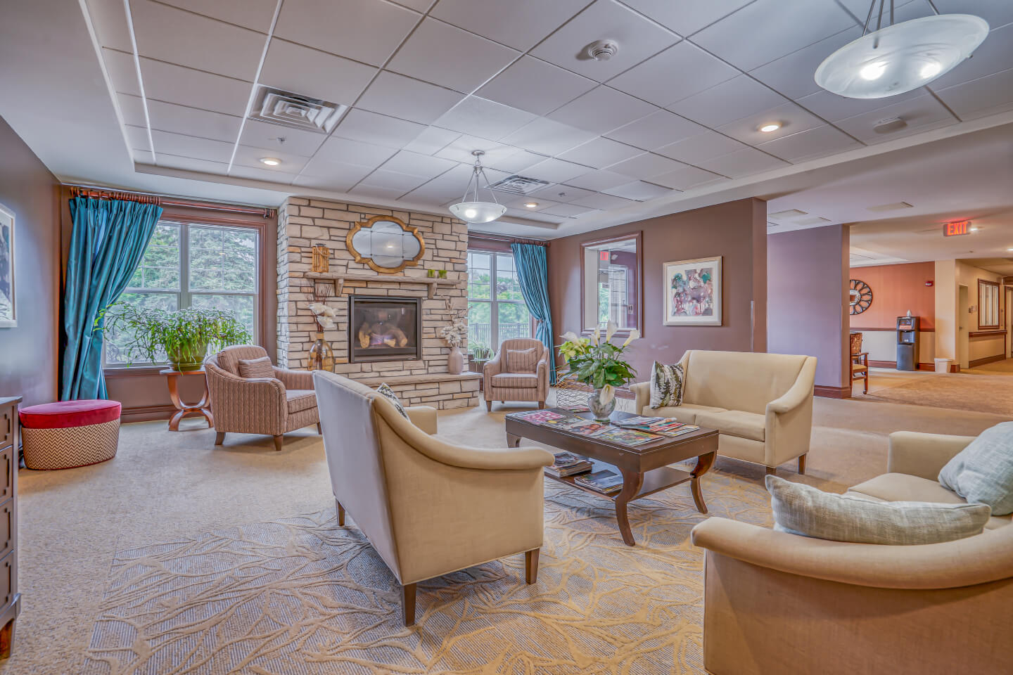 Comfortable seating area with fireplace, armchairs, and sofas in a senior communitys common area.