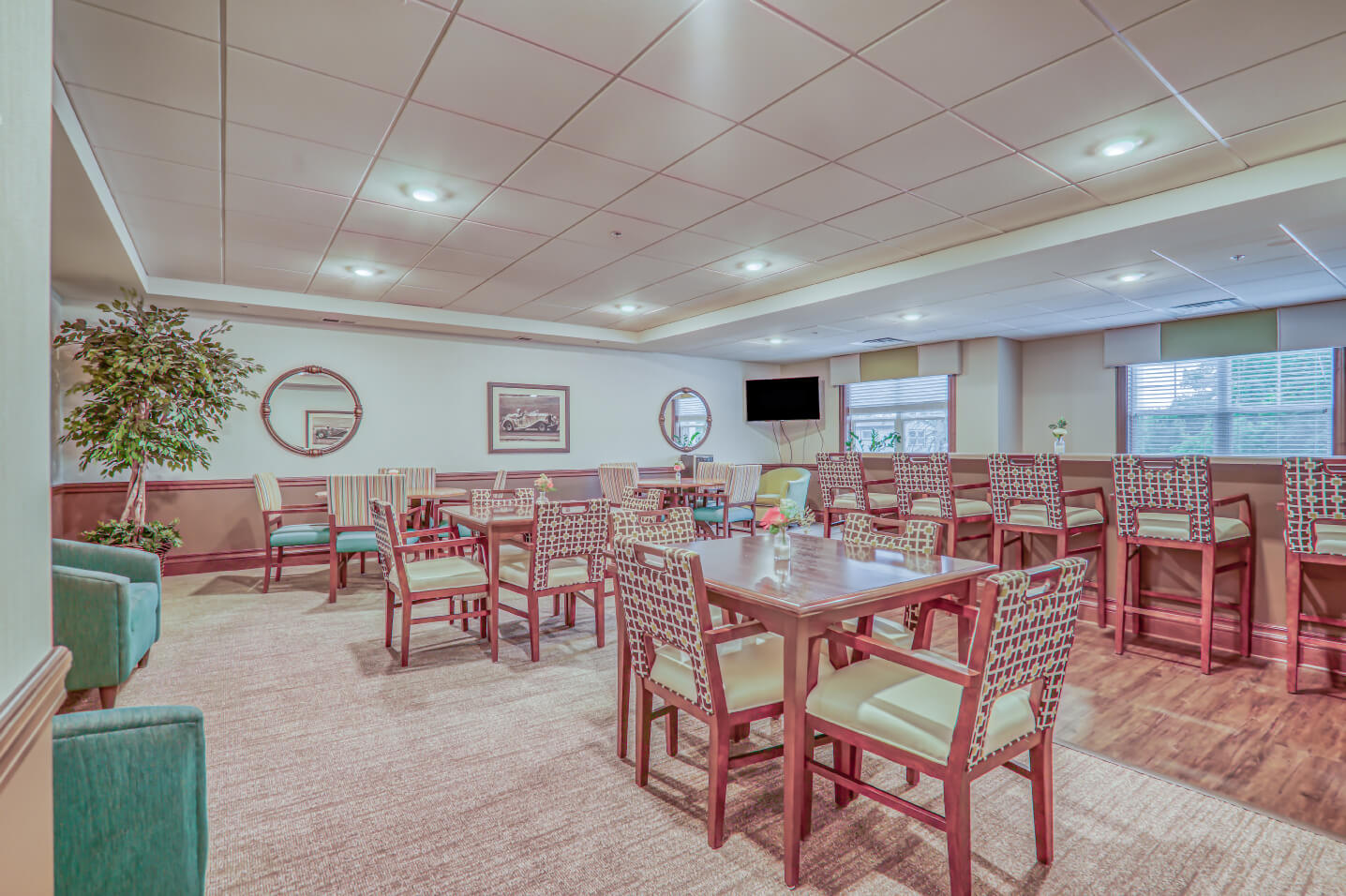 Dining area with chairs and tables in a senior living community with modern decor and large windows.