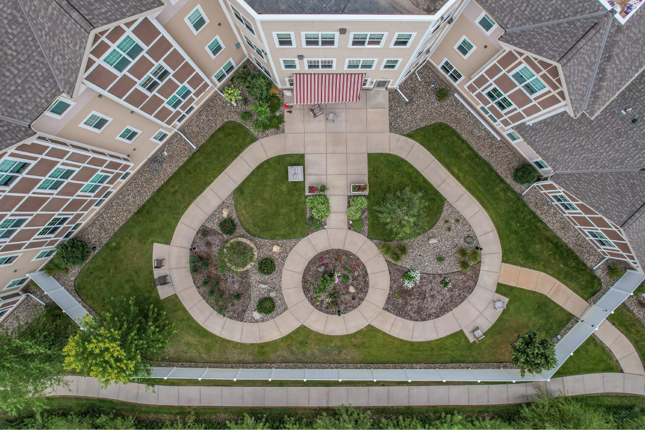 Aerial view of courtyard with pathways, landscaping, and seating area at a senior living community.