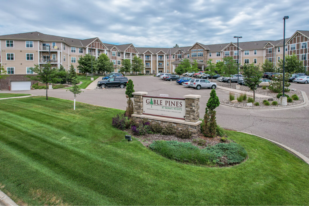 Entrance of Gable Pines featuring well-maintained landscaping and parking area.