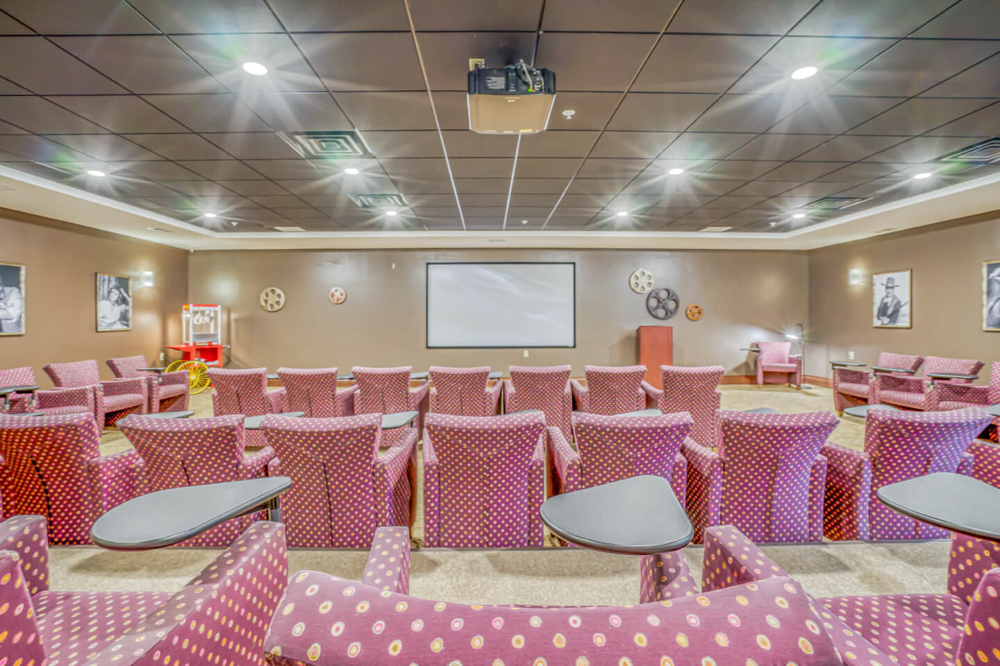 Movie theater room at Gable Pines senior living community with red and yellow chairs.