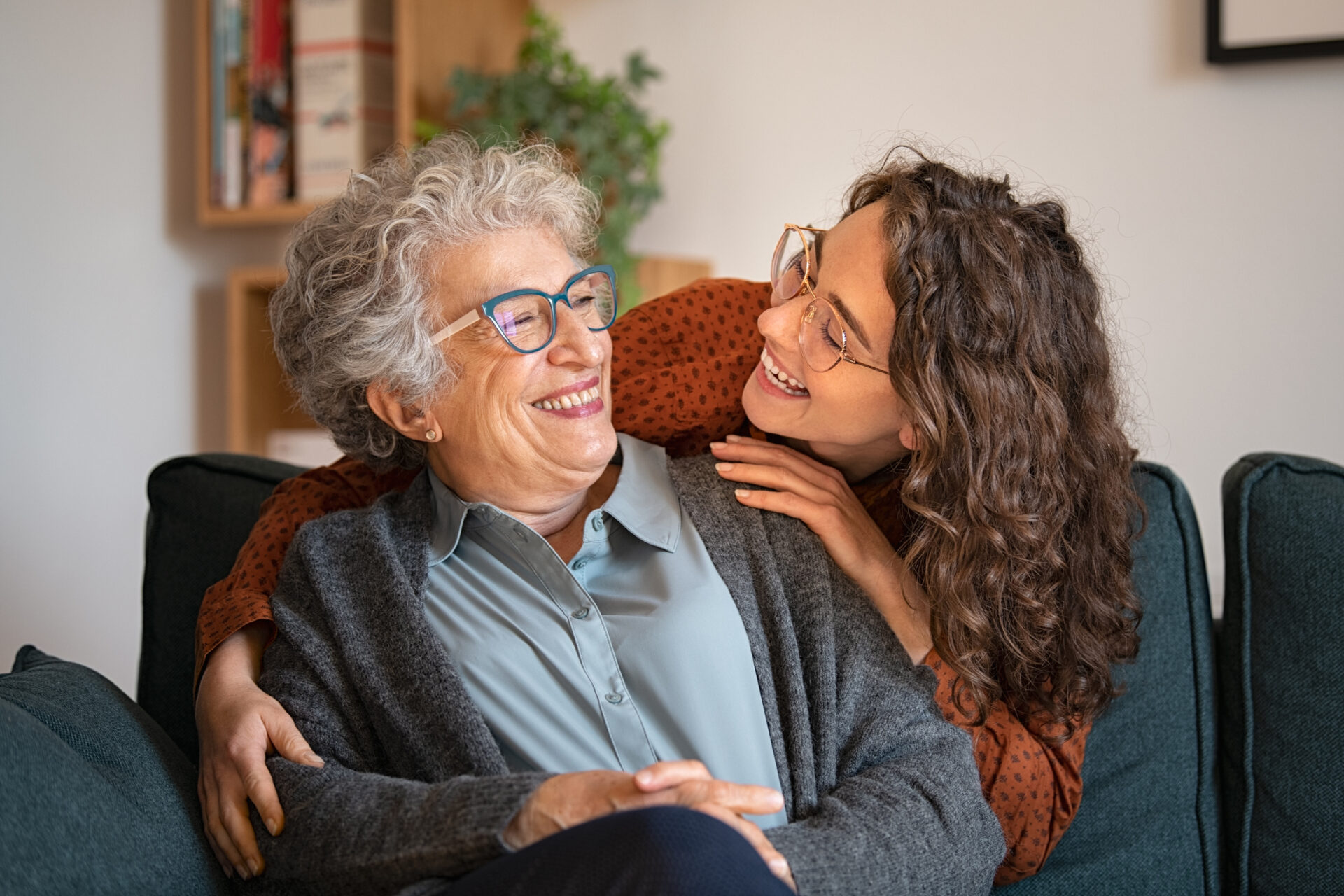 Resident enjoying a warm moment with a visitor in a senior living community lounge area.