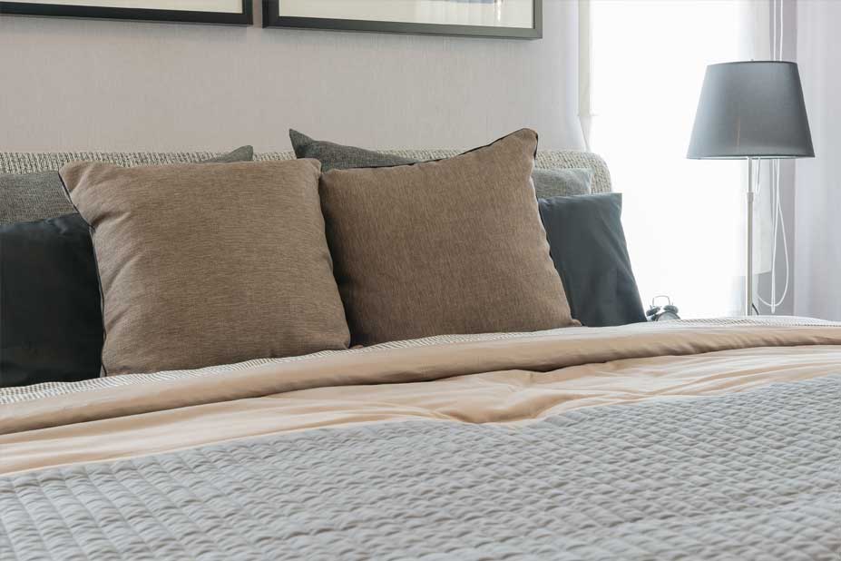 pillows on a bed with lamp on bedside table