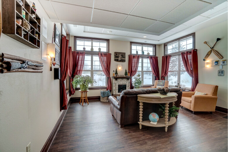 Cozy common area with fireplace and large windows in a senior living community unit.