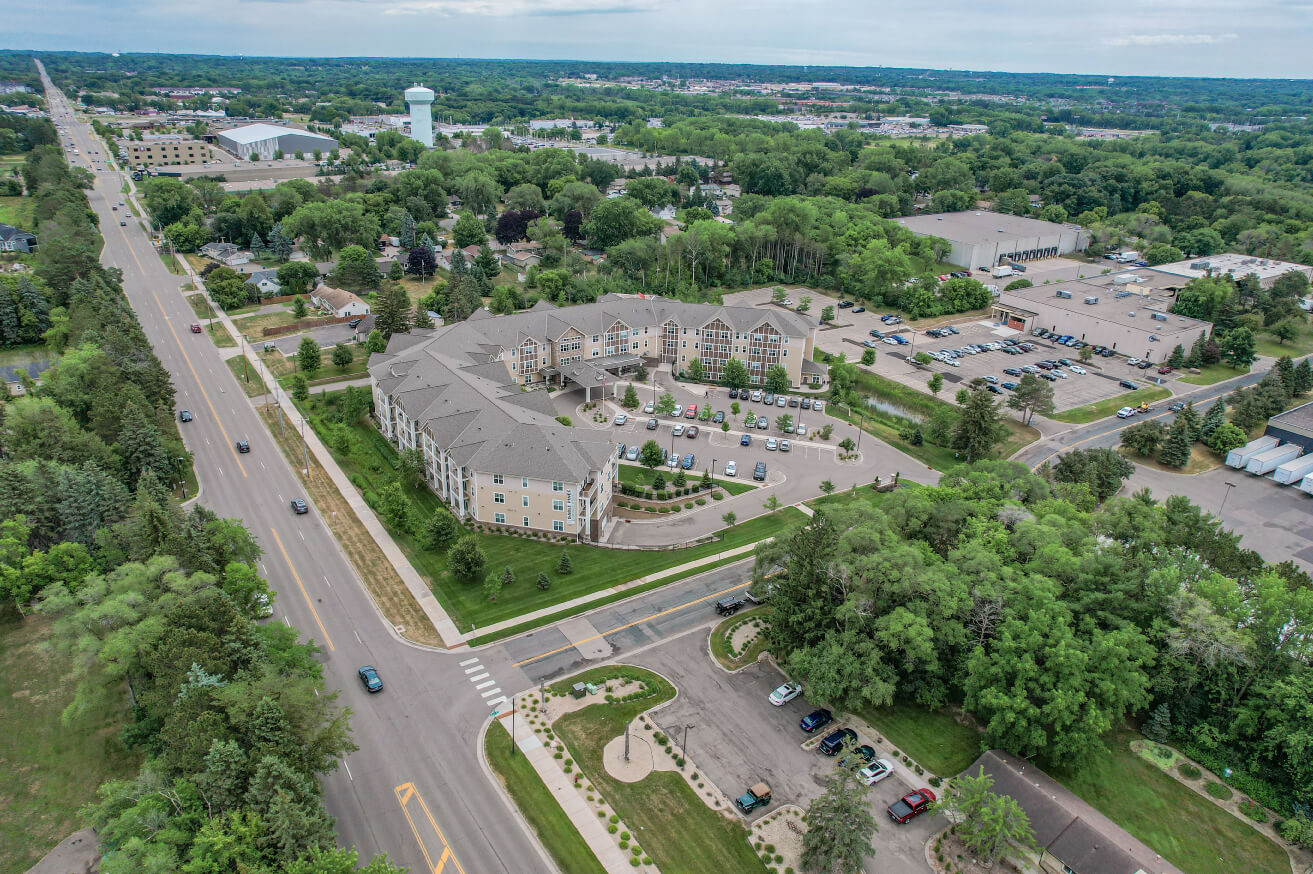 Aerial view of a senior living community with a large, multi-story building and parking lot.