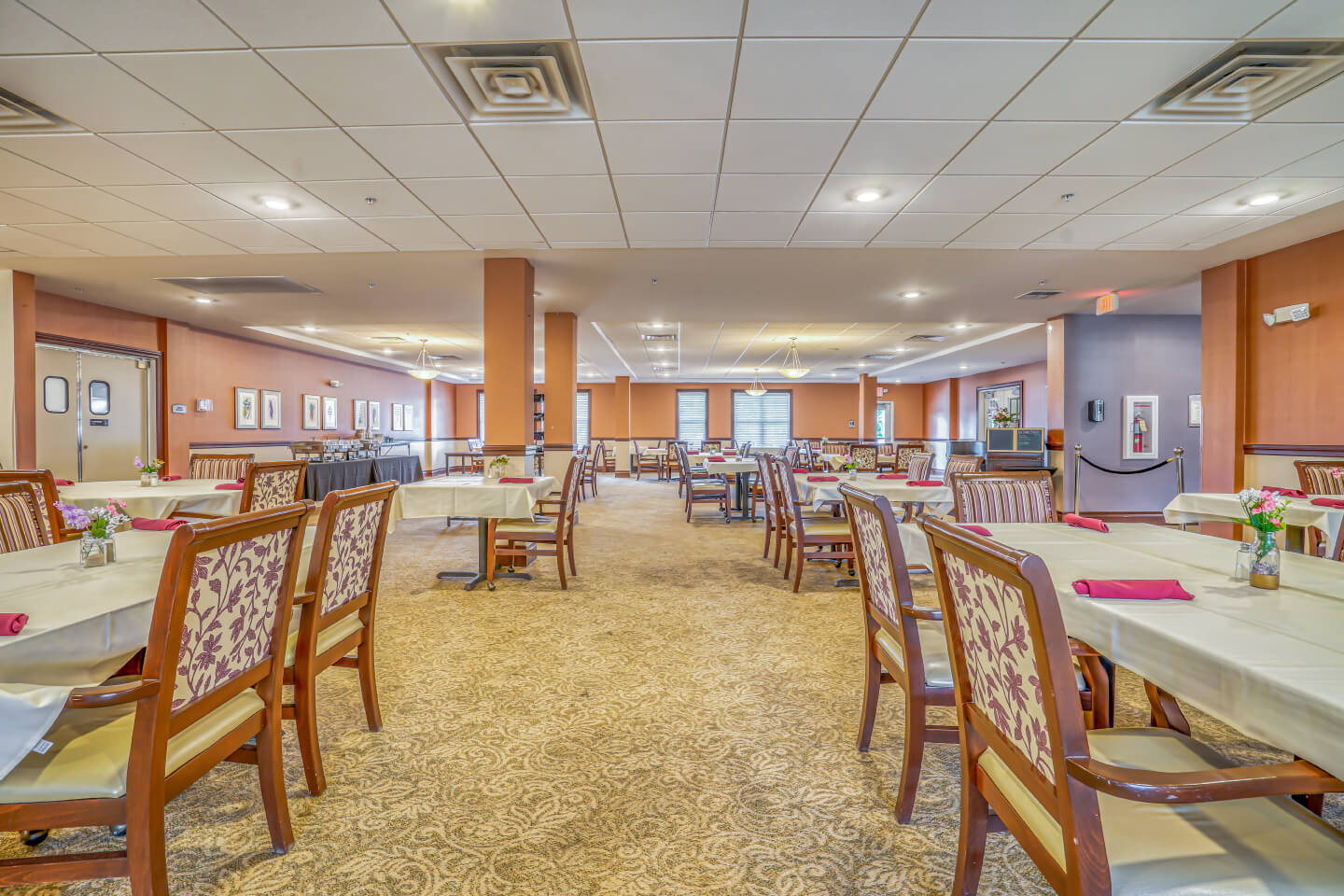 Dining area with wooden chairs and tables at a senior living community.