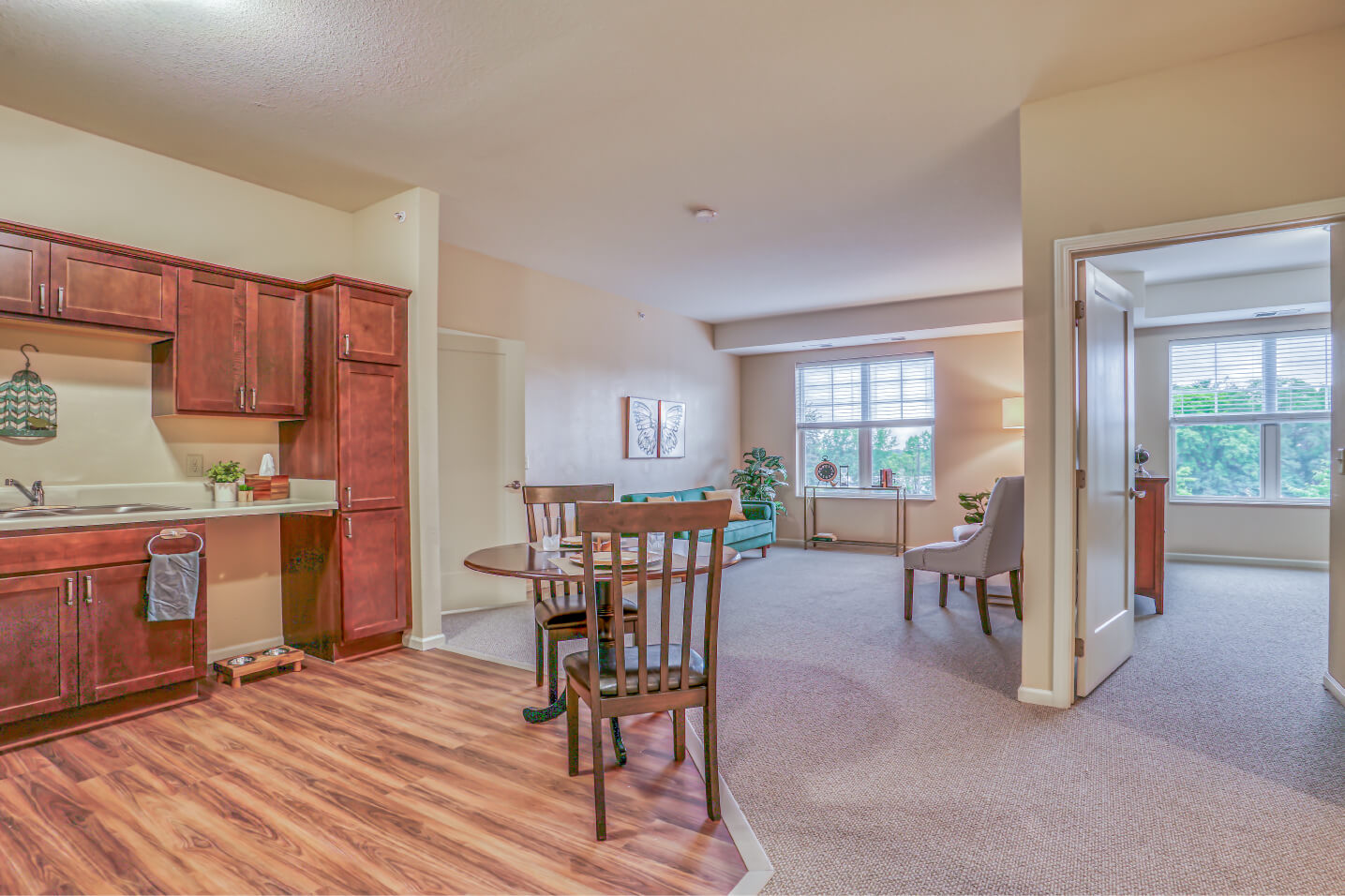 Spacious unit with open living area, kitchen with wooden cabinets, and large windows.