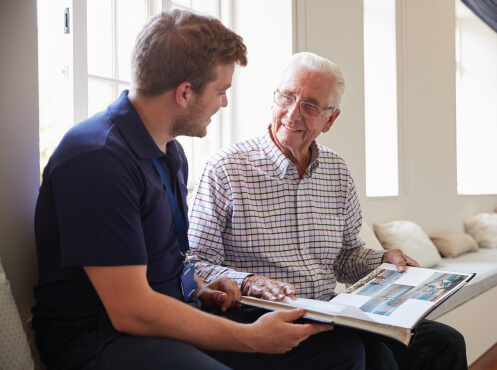 staff member reading a book with a senior man