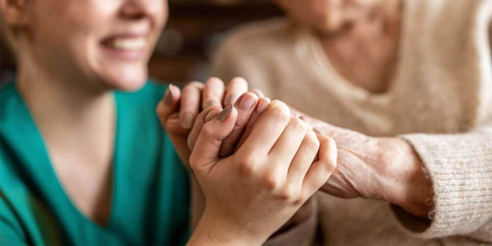 Close up of caregiver holding senior woman's hands